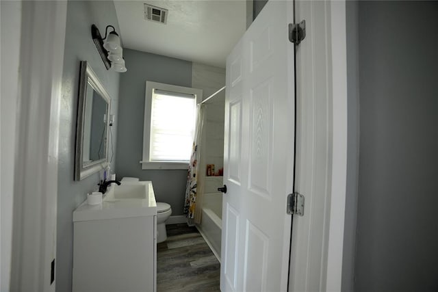 full bathroom with visible vents, wood finished floors, vanity, toilet, and shower / tub combo with curtain