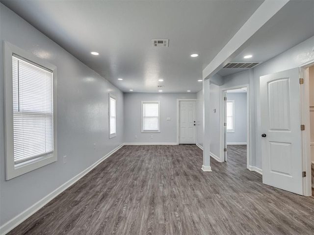 interior space with dark wood-type flooring, visible vents, and baseboards