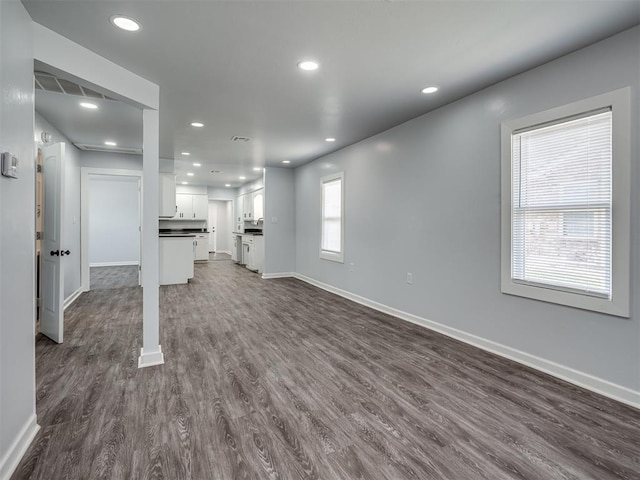 unfurnished living room featuring dark wood-type flooring, visible vents, baseboards, and recessed lighting