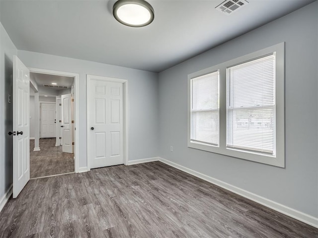 unfurnished bedroom featuring dark wood-type flooring, visible vents, and baseboards