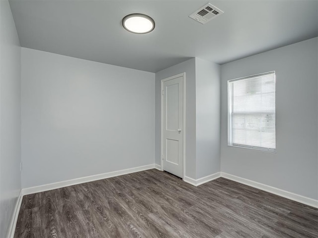 spare room with dark wood-type flooring, baseboards, and visible vents