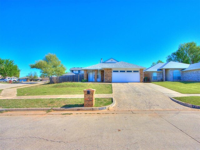 ranch-style house featuring a front yard, an attached garage, fence, concrete driveway, and brick siding