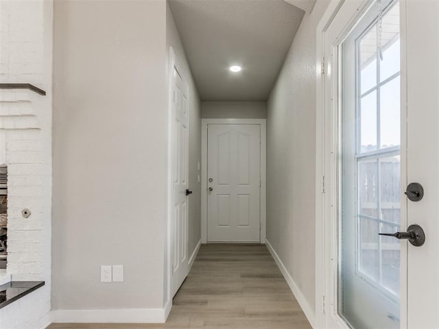 corridor featuring light wood-type flooring and baseboards