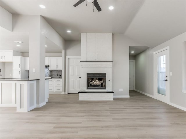 unfurnished living room with recessed lighting, a fireplace, a ceiling fan, light wood-style floors, and lofted ceiling