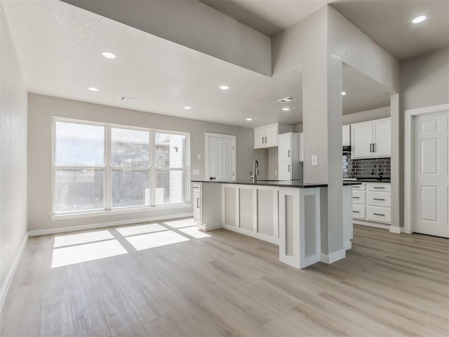 kitchen featuring white cabinets, light wood-style flooring, baseboards, and dark countertops
