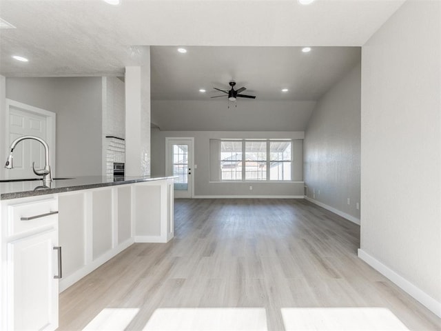 kitchen featuring ceiling fan, white cabinets, recessed lighting, a sink, and baseboards
