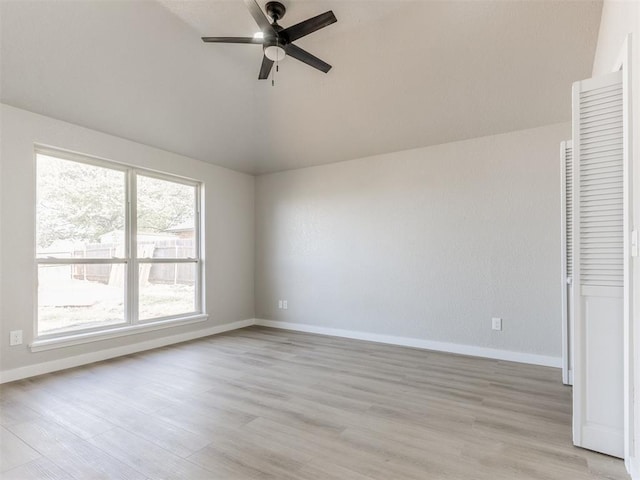 unfurnished bedroom featuring light wood-style flooring, baseboards, vaulted ceiling, and a ceiling fan