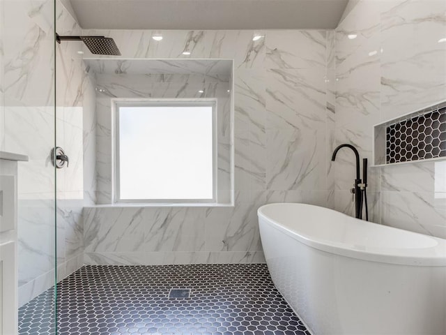 bathroom featuring a freestanding bath, a marble finish shower, and tile walls