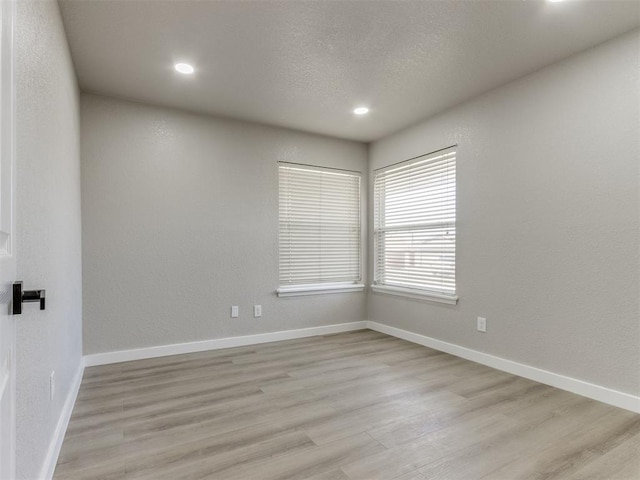 spare room with baseboards, light wood-type flooring, recessed lighting, and a textured ceiling