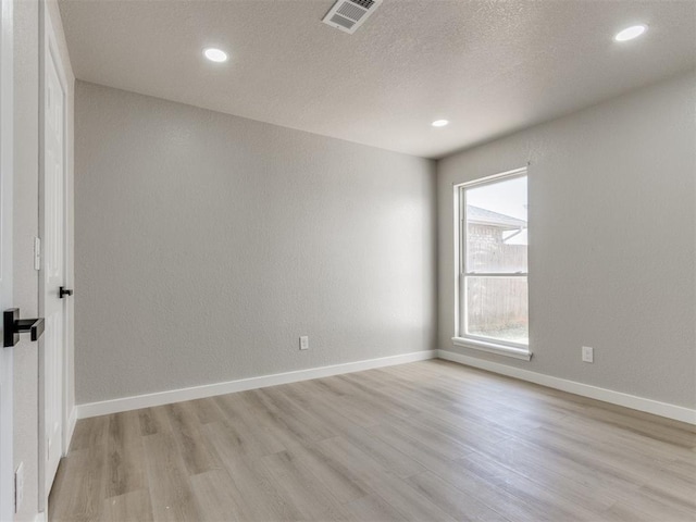unfurnished room with light wood-style flooring, baseboards, visible vents, and recessed lighting