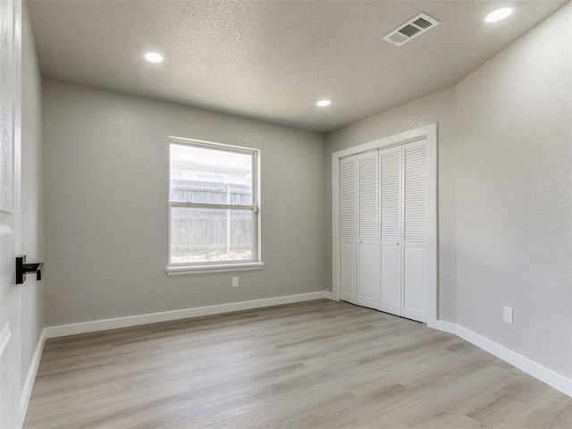 unfurnished bedroom with recessed lighting, visible vents, a closet, and light wood-style flooring