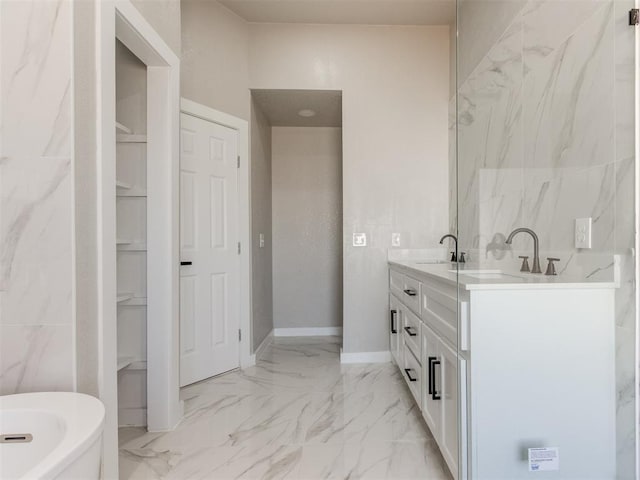full bath with a sink, a freestanding bath, marble finish floor, and double vanity
