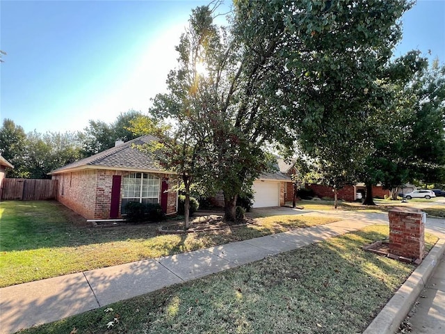 view of front facade featuring roof with shingles, a front yard, brick siding, a garage, and fence