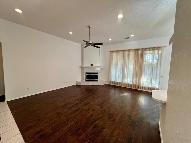 unfurnished living room with visible vents, a tiled fireplace, ceiling fan, recessed lighting, and dark wood-type flooring