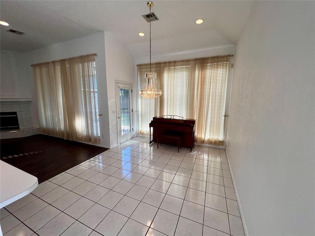 foyer with visible vents, light tile patterned floors, a tiled fireplace, a chandelier, and recessed lighting