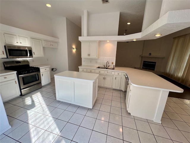 kitchen with tasteful backsplash, a sink, light countertops, appliances with stainless steel finishes, and a peninsula