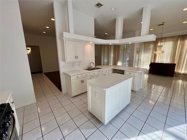 kitchen with a peninsula, visible vents, light tile patterned flooring, light countertops, and range with gas stovetop