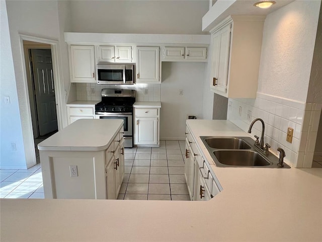 kitchen with white cabinetry, light tile patterned flooring, decorative backsplash, stainless steel appliances, and a sink