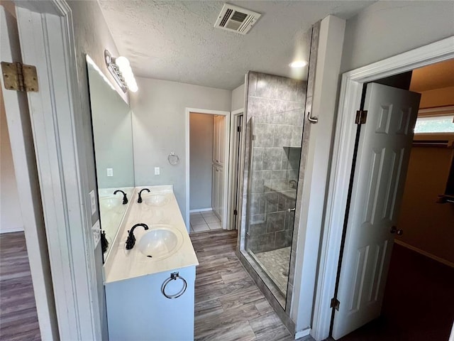 full bath with visible vents, a sink, a stall shower, and wood finished floors