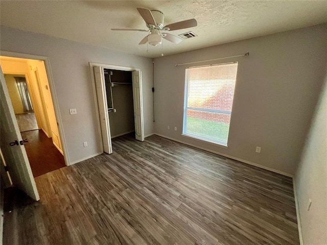 unfurnished bedroom with ceiling fan, dark wood-type flooring, a closet, visible vents, and baseboards