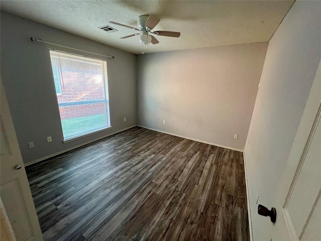 empty room featuring dark wood-type flooring, visible vents, ceiling fan, and baseboards