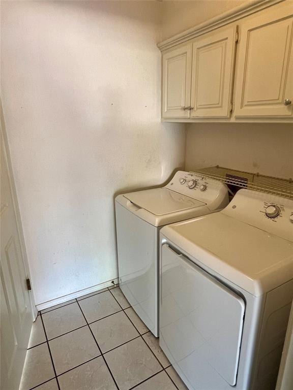 laundry area with light tile patterned floors, washing machine and dryer, and cabinet space