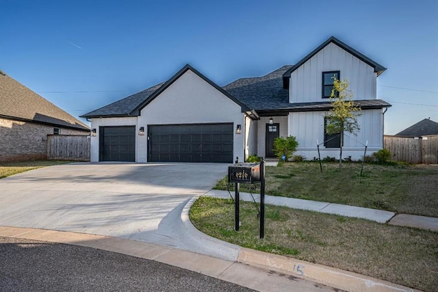 modern farmhouse style home with concrete driveway, board and batten siding, a front lawn, an attached garage, and fence
