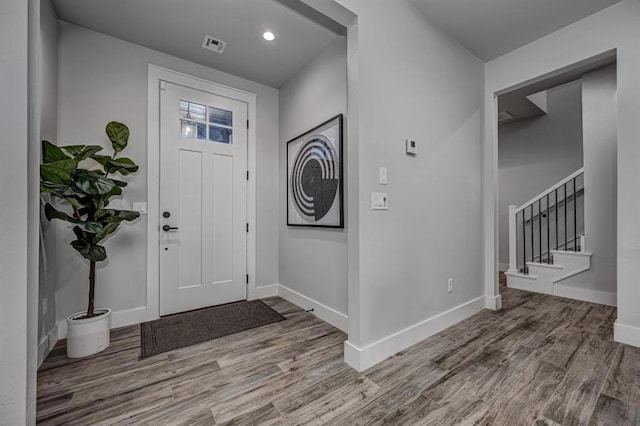 entryway featuring wood finished floors, baseboards, visible vents, and stairway