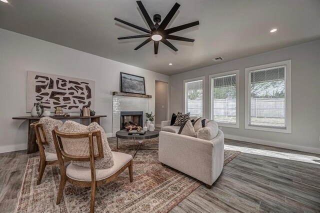 living room featuring baseboards, a fireplace, visible vents, ceiling fan, and wood finished floors