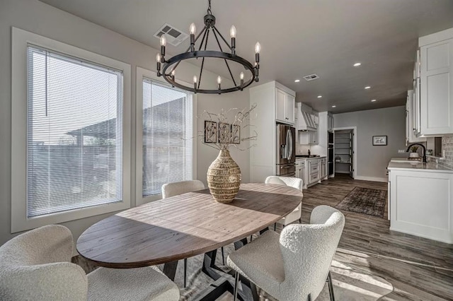 dining space featuring a chandelier, visible vents, dark wood-style flooring, and baseboards