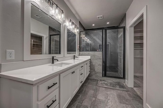bathroom with a shower stall, a sink, a spacious closet, and visible vents