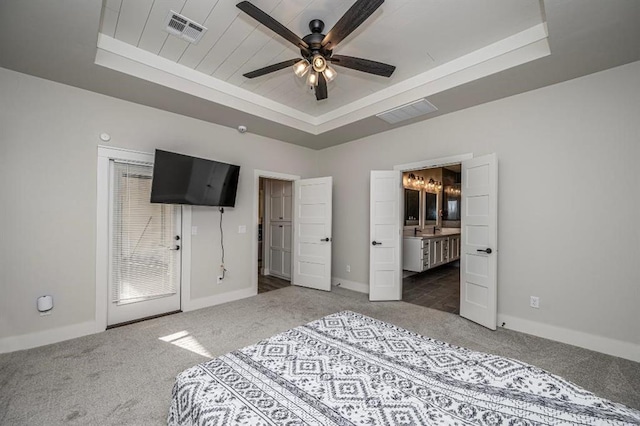 unfurnished bedroom featuring visible vents, baseboards, carpet, a tray ceiling, and ensuite bath