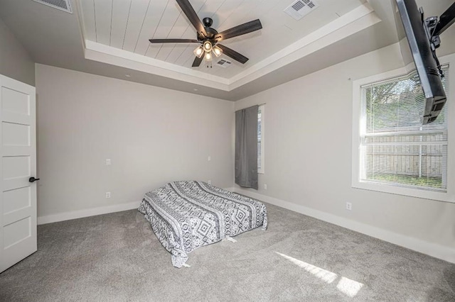 unfurnished bedroom featuring visible vents, a tray ceiling, multiple windows, and carpet floors