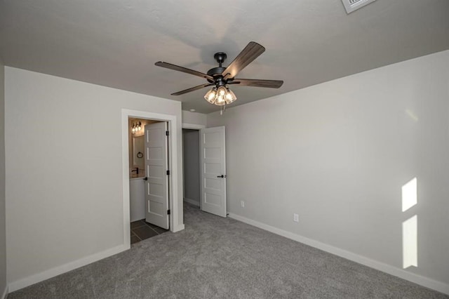 unfurnished bedroom featuring ensuite bathroom, baseboards, a ceiling fan, and carpet
