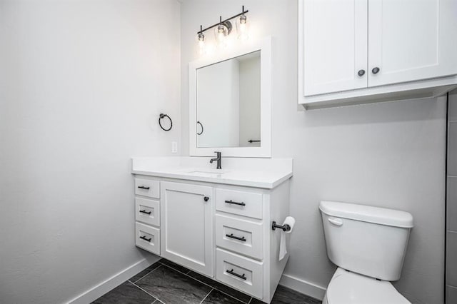 bathroom with toilet, vanity, baseboards, and marble finish floor