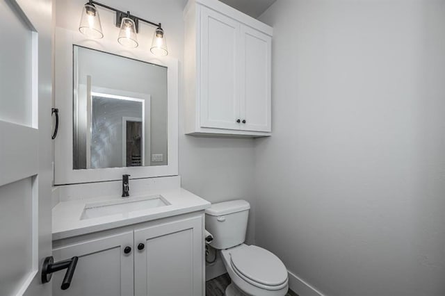 half bathroom featuring toilet, vanity, and baseboards