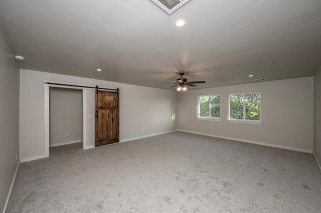 unfurnished bedroom with visible vents, baseboards, carpet, and a barn door