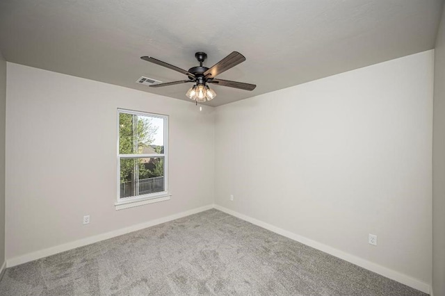 carpeted spare room with visible vents, baseboards, and a ceiling fan