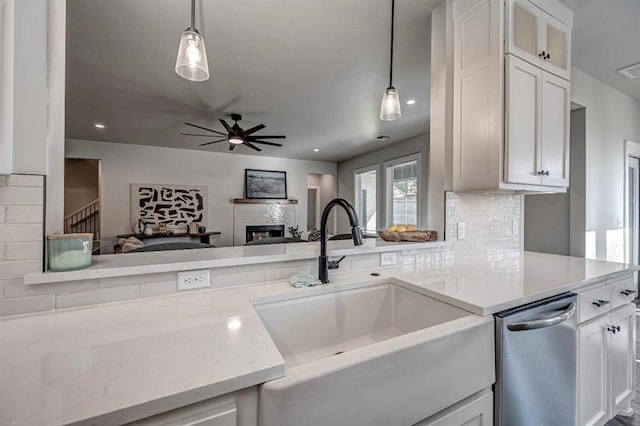 kitchen with a fireplace, a ceiling fan, white cabinets, a sink, and hanging light fixtures