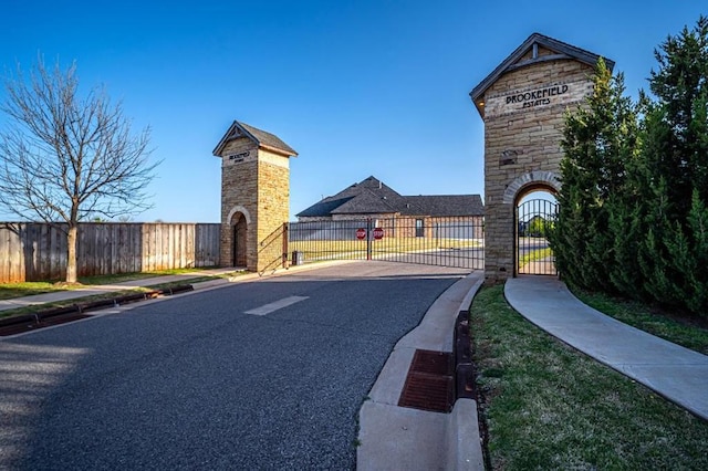 view of street with sidewalks, a gated entry, curbs, and a gate