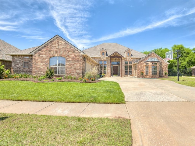 french provincial home featuring concrete driveway, brick siding, an attached garage, and a front lawn