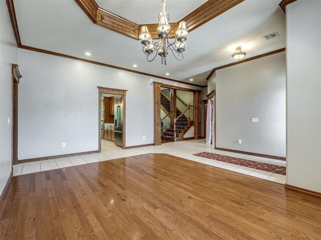 unfurnished room featuring crown molding, visible vents, light wood-style floors, and a notable chandelier