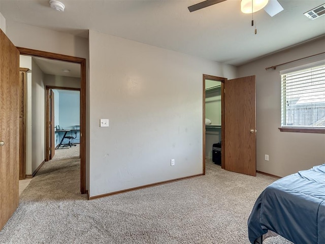 bedroom with ceiling fan, light carpet, baseboards, a spacious closet, and visible vents