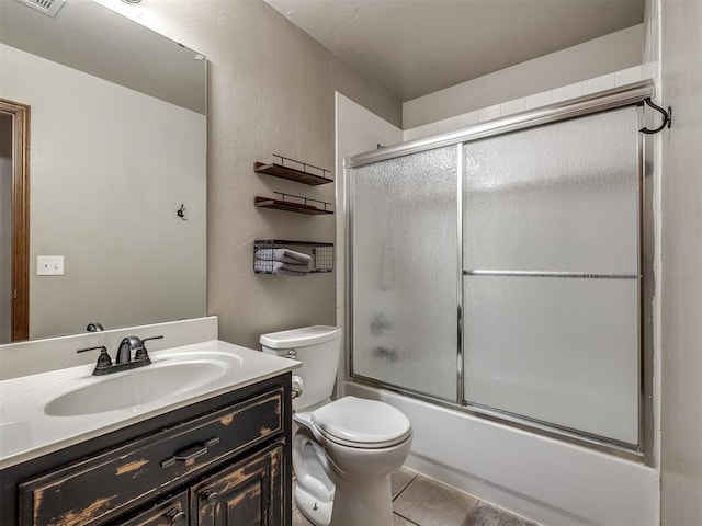 bathroom with shower / bath combination with glass door, a textured wall, vanity, toilet, and tile patterned floors