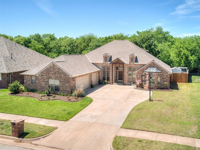 french country style house with a garage, brick siding, fence, a front lawn, and concrete driveway