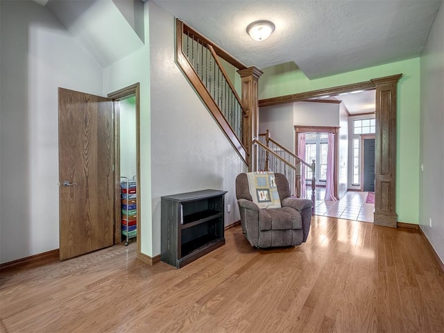 sitting room with stairs, baseboards, and light wood-type flooring