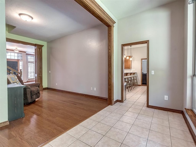 interior space with light tile patterned floors, baseboards, and decorative columns