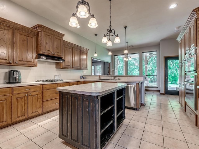 kitchen featuring a sink, appliances with stainless steel finishes, a peninsula, and light countertops