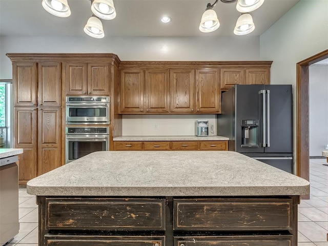 kitchen with light tile patterned floors, appliances with stainless steel finishes, brown cabinetry, and light countertops
