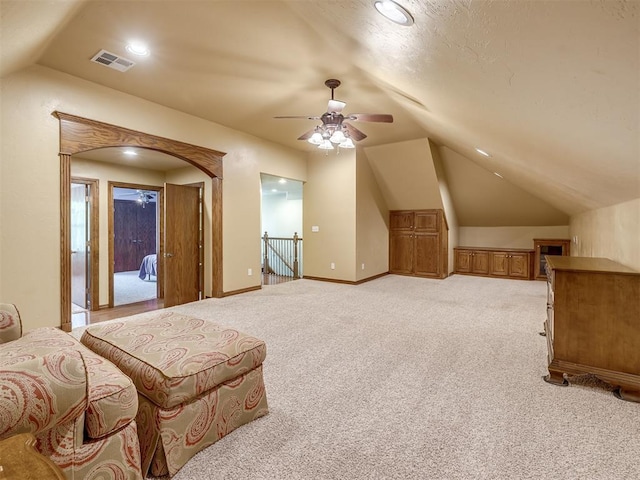 interior space featuring light colored carpet, a ceiling fan, baseboards, lofted ceiling, and visible vents